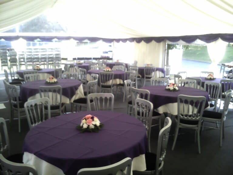 Marquee event setup with purple tablecloths and floral centrepieces in Leicester.